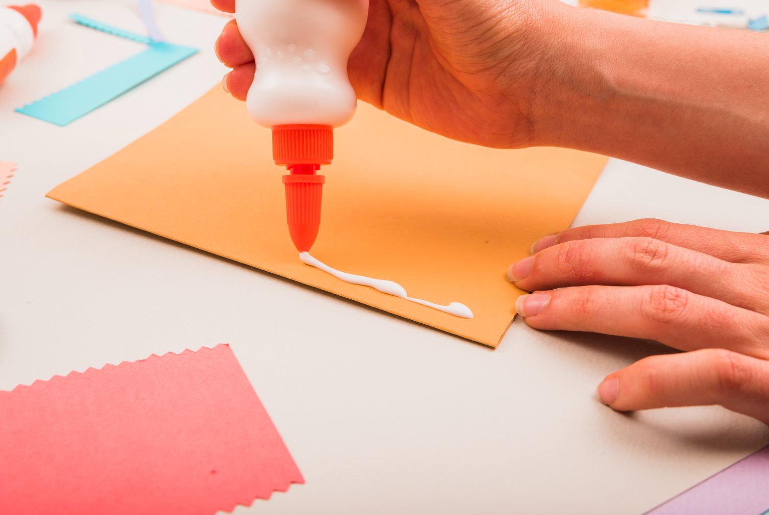 A hand applying super glue glue on paper